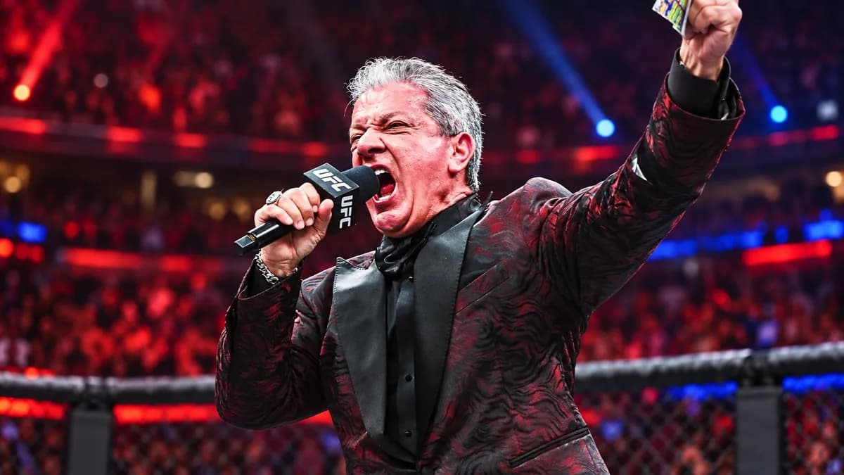 Bruce Buffer con el micrófono de UFC y un brazo levantado durante una presentación en el octágono.