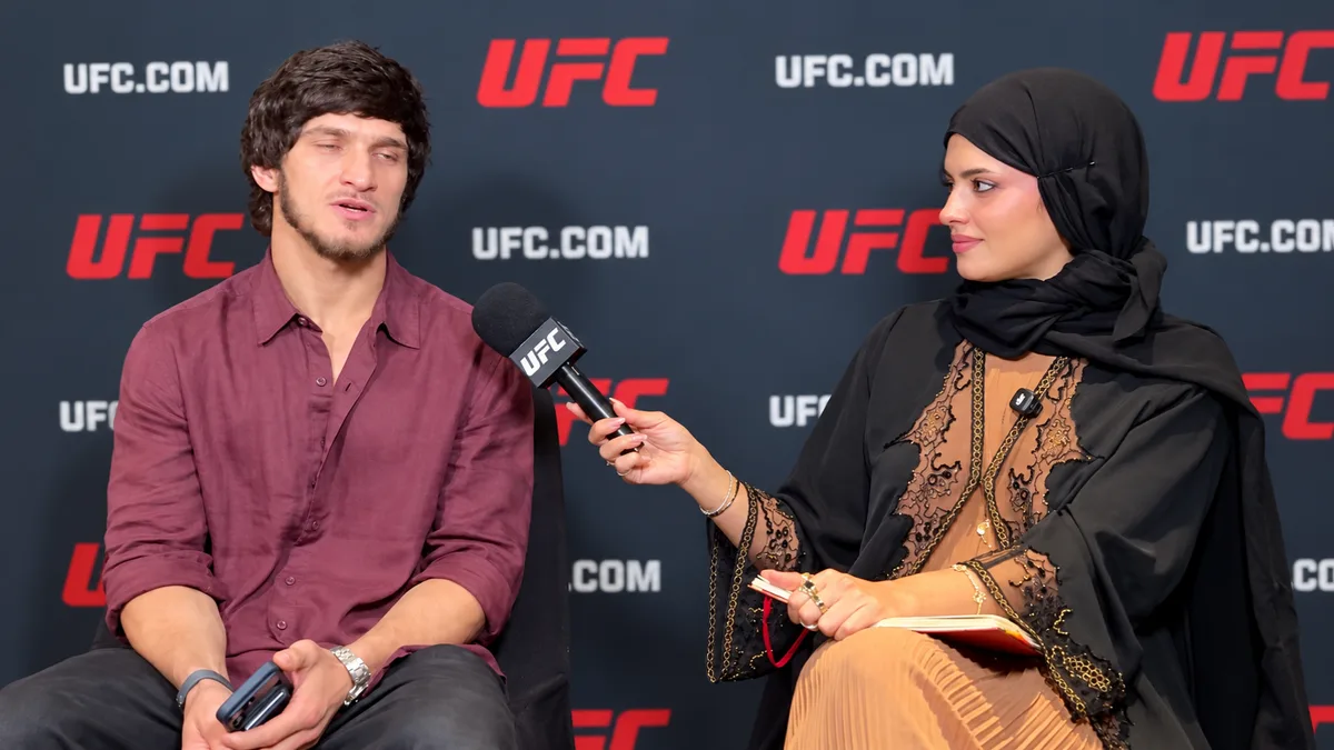 Movsar Evloev durante una entrevista con Nina Drama, quien lleva un pañuelo negro y sostiene un micrófono de UFC.